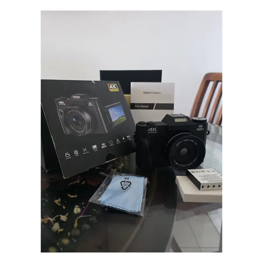 Open Box 4K UHD digital vlogging camera beside its original box, with rechargeable battery, cleaning cloth and user manual