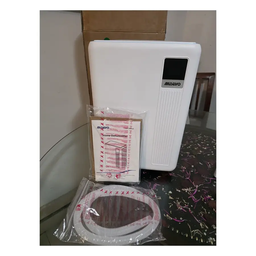 Open Box Aiusevo AS300 dehumidifier in white with its digital display, beside the bagged user manual and drain hose, in front of the opened box