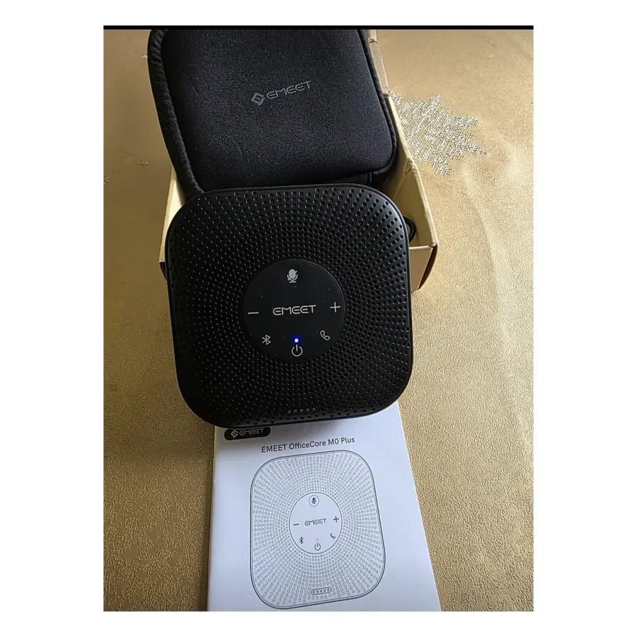 EMEET M0 Plus speakerphone powered on with its carrying pouch and user manual