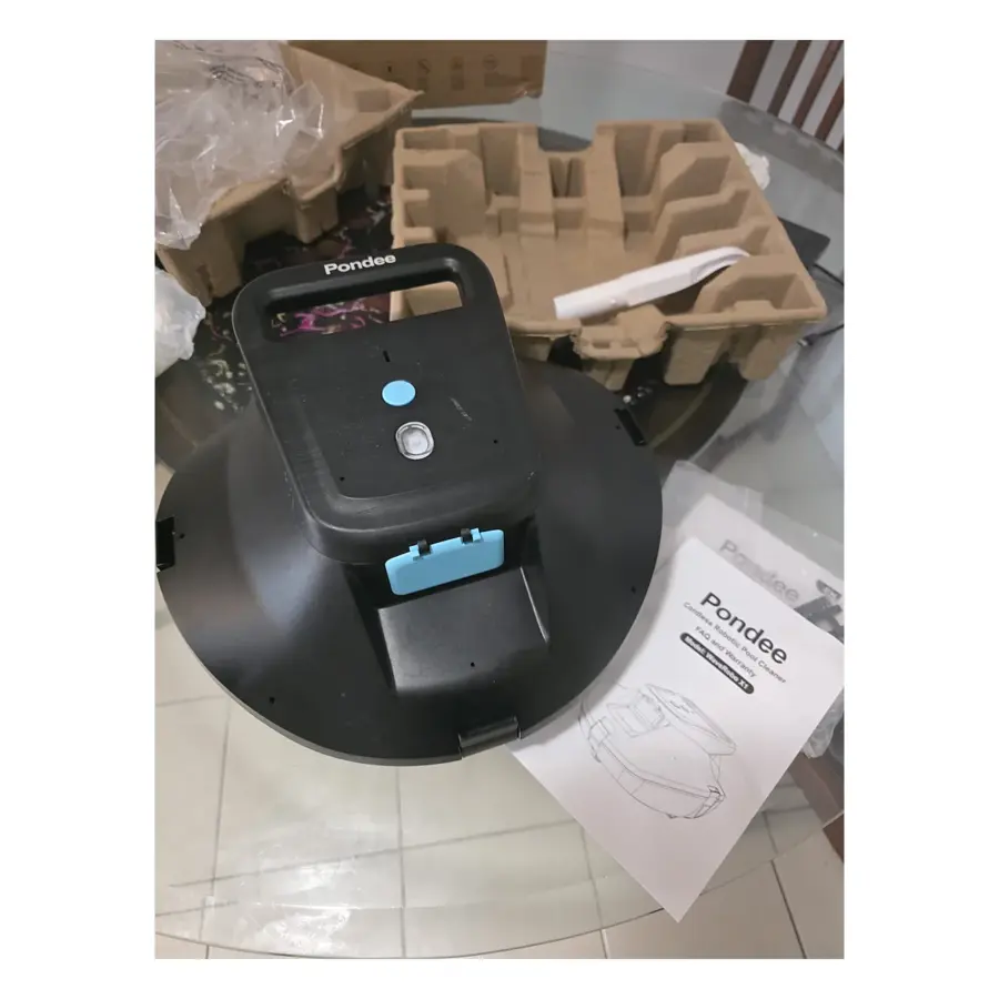 Unboxed Pondee WaveRobo X1 pool cleaner with carry handle, beside the white retrieval hook and user manual