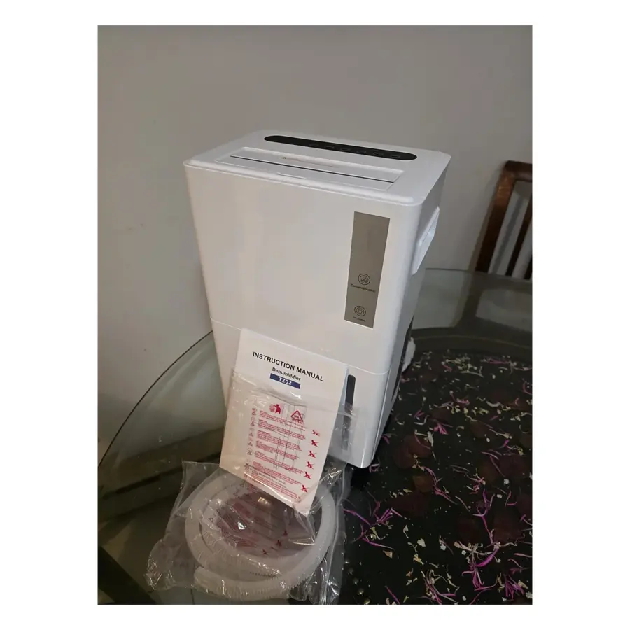 Open Box TZ02 white dehumidifier with touch control panel on top and Dehumidification and Dry clothes labels, beside its instruction manual and drain hose